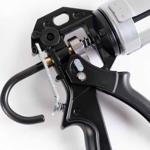 A black and silver gun resting on a flat surface, surrounded by metalware items.